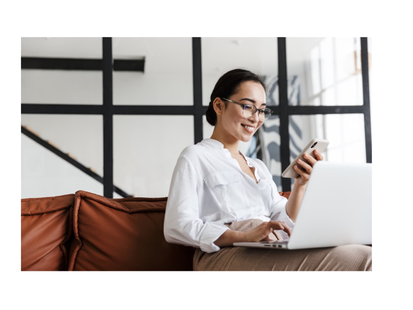 A woman works across a laptop and phone at once.
